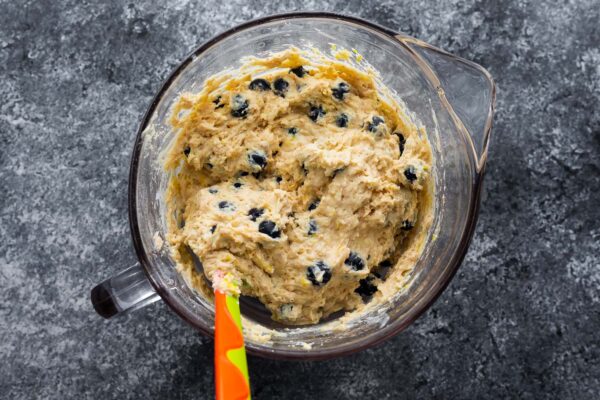 blueberry muffin batter mixed up in glass bowl with spatula