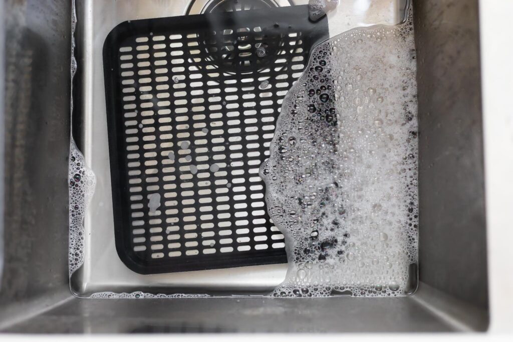 air fryer oven tray soaking in soapy water