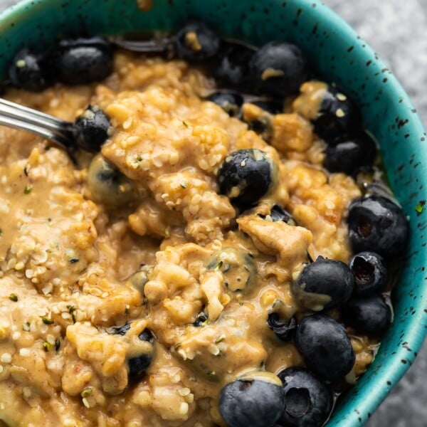 close up view oatmeal in blue bowl with peanut butter and blueberries