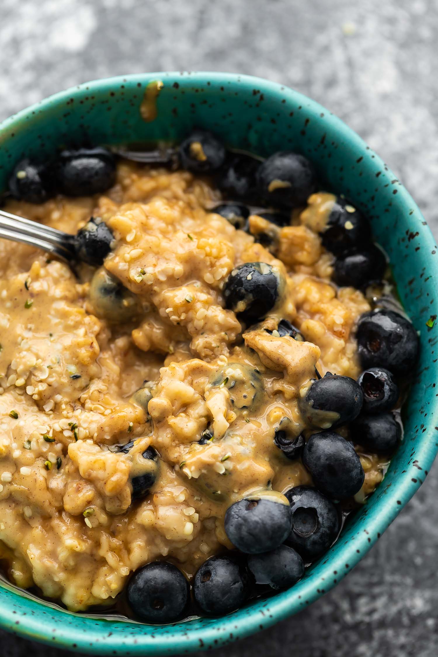 close up view oatmeal in blue bowl with peanut butter and blueberries