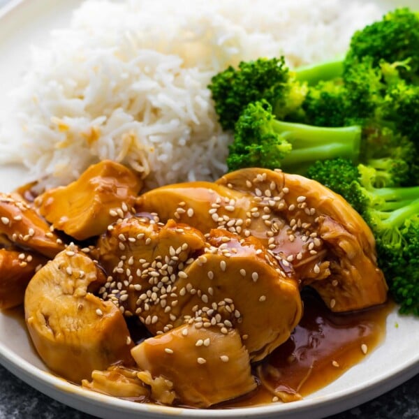 close up view of chicken teriyaki on white plate with broccoli and rice