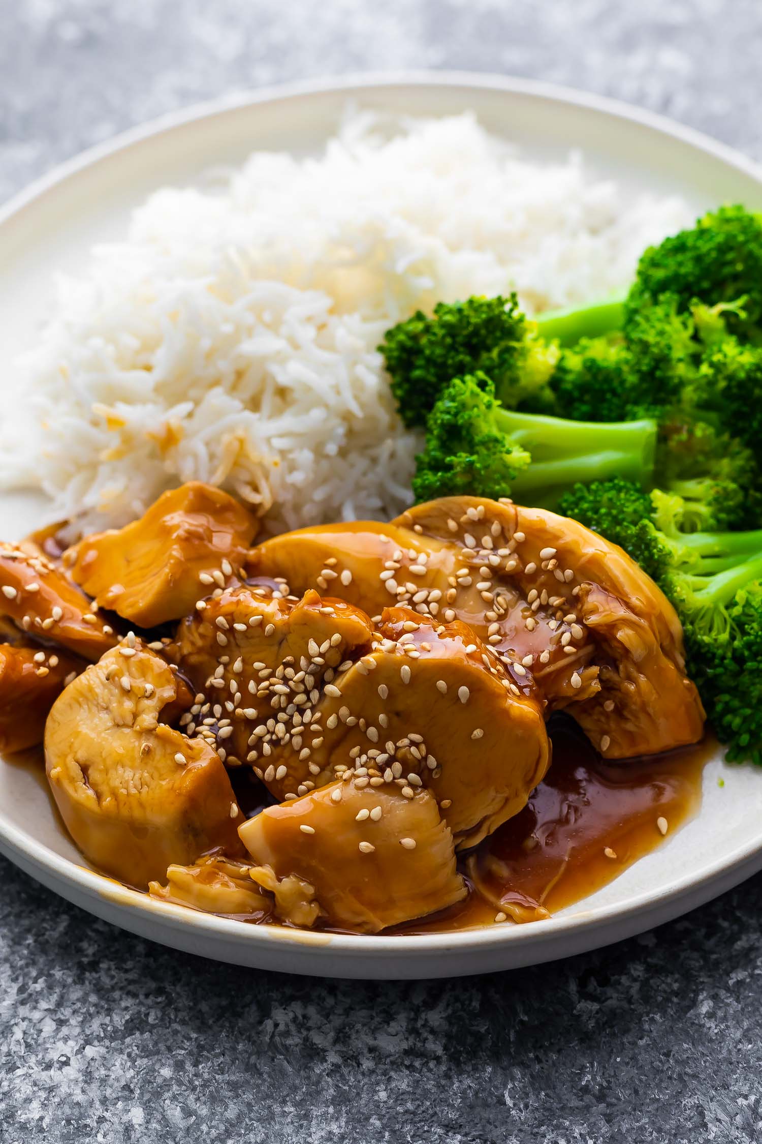 close up view of chicken teriyaki on white plate with broccoli and rice