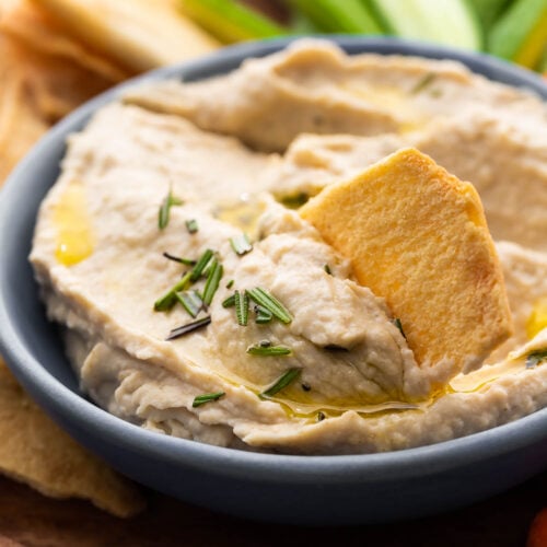 close up view of pita chip in white bean dip