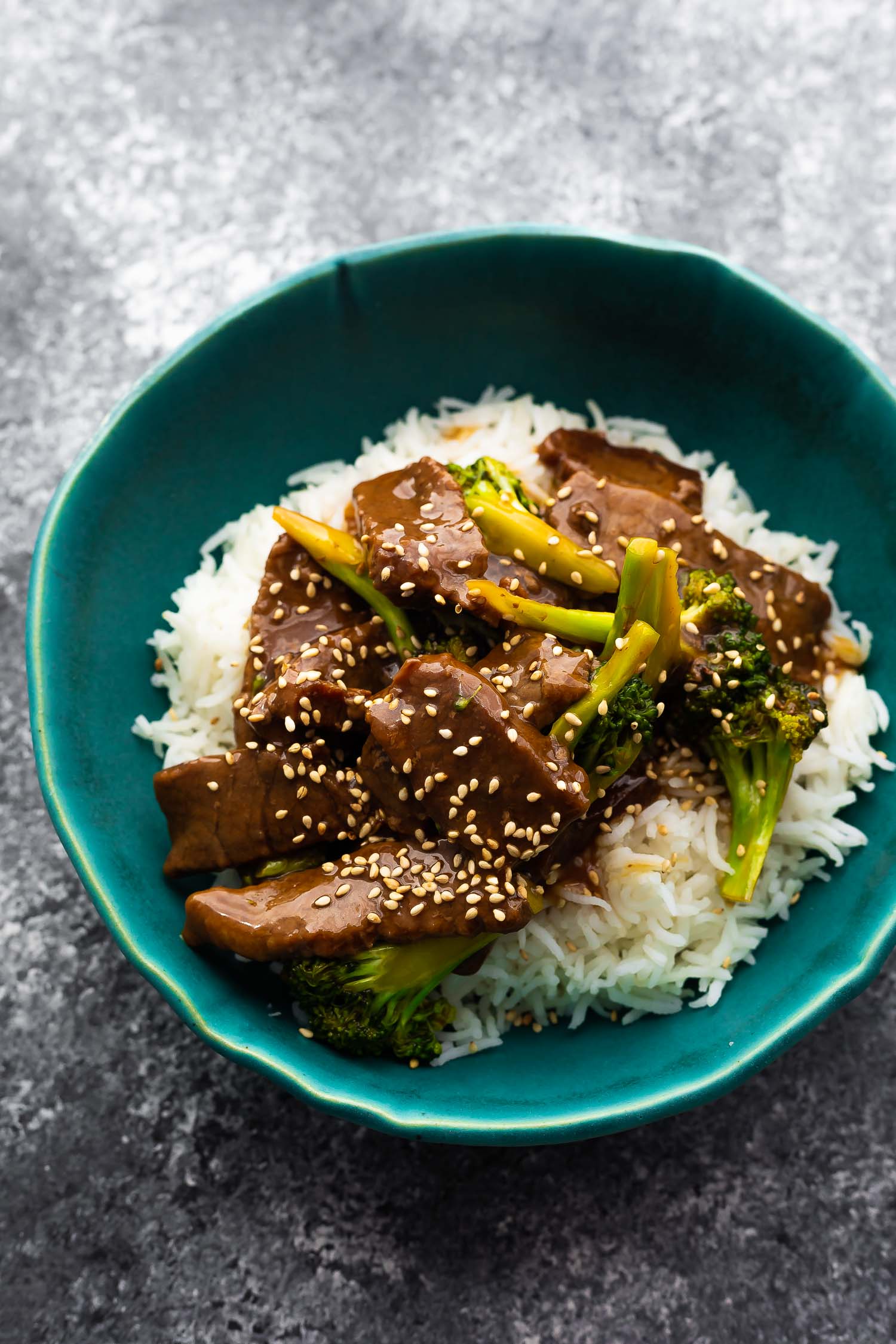 beef and broccoli served over rice in blue bowl