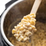 close up shot of macaroni and cheese on spoon, lifted above instant pot