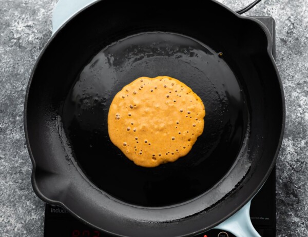 pumpkin pancake cooking in black pan