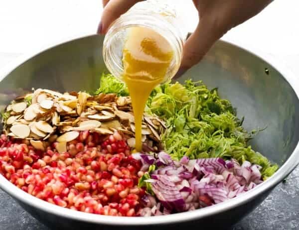 pouring vinaigrette over brussels sprouts salad