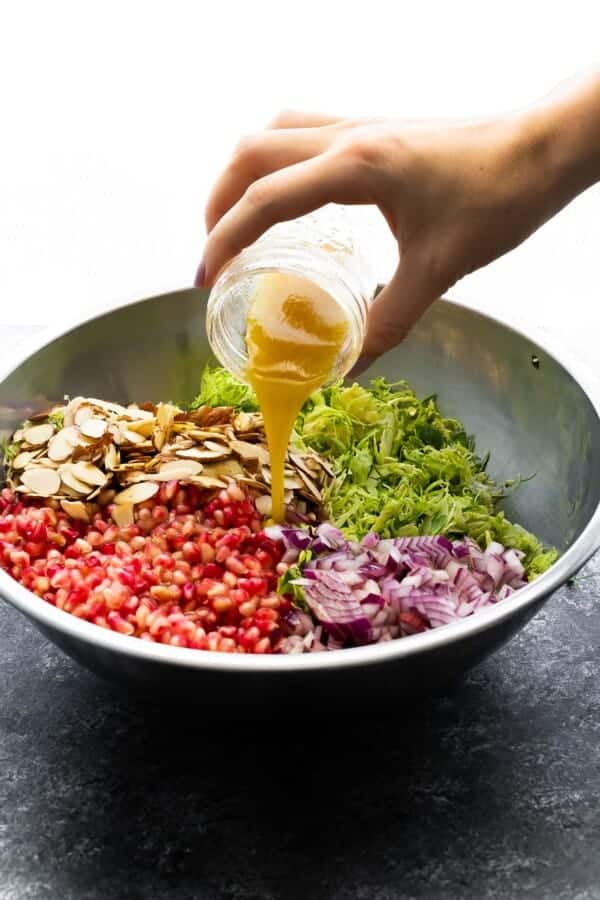 pouring vinaigrette over brussels sprouts salad