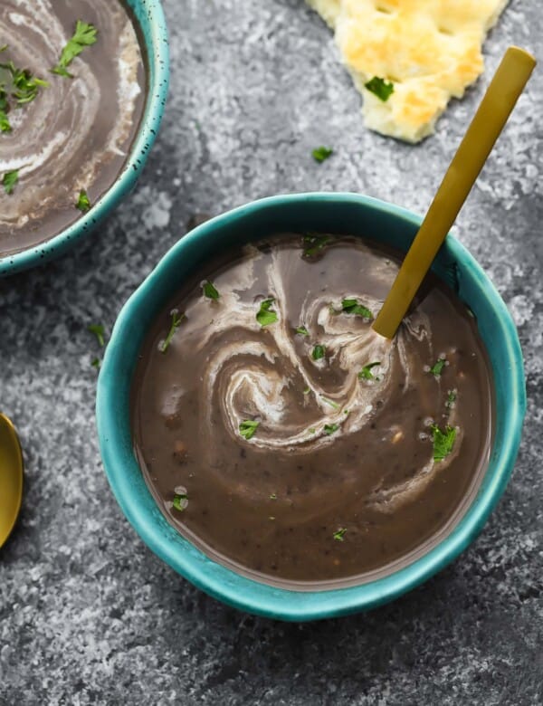 black bean soup in blue bowl swirled with cream
