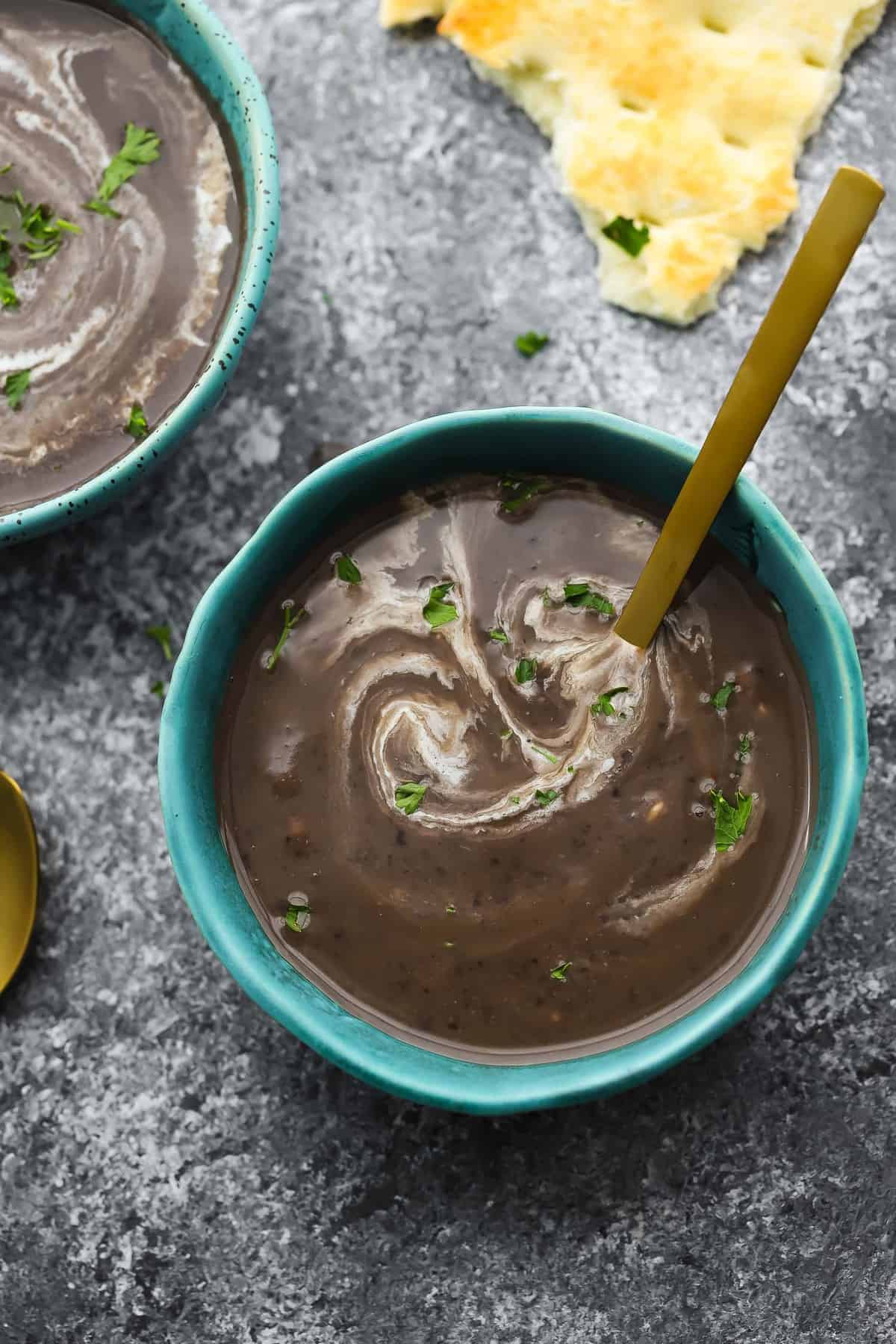 black bean soup in blue bowl swirled with cream