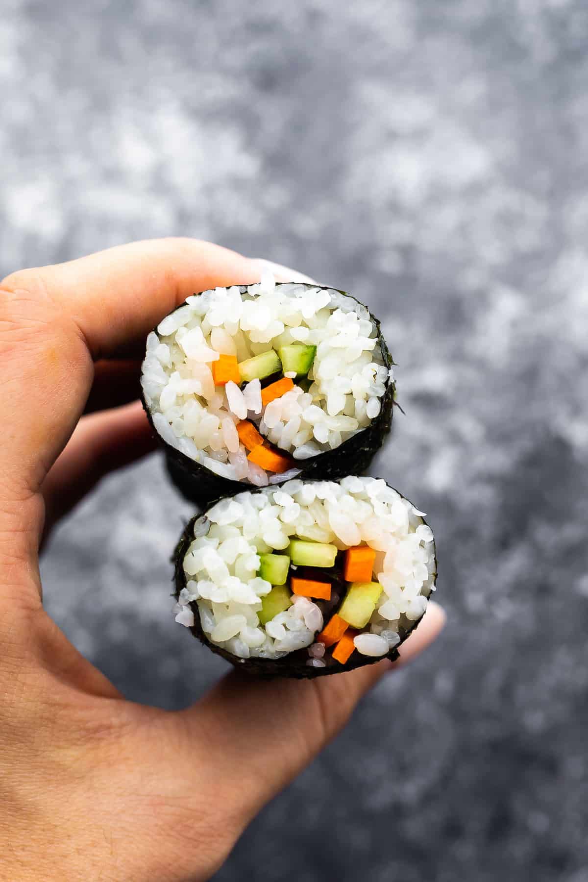 sushi roll sliced in half and held by hand