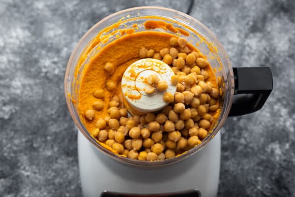 chickpeas added to other ingredients for pumpkin hummus in food processor