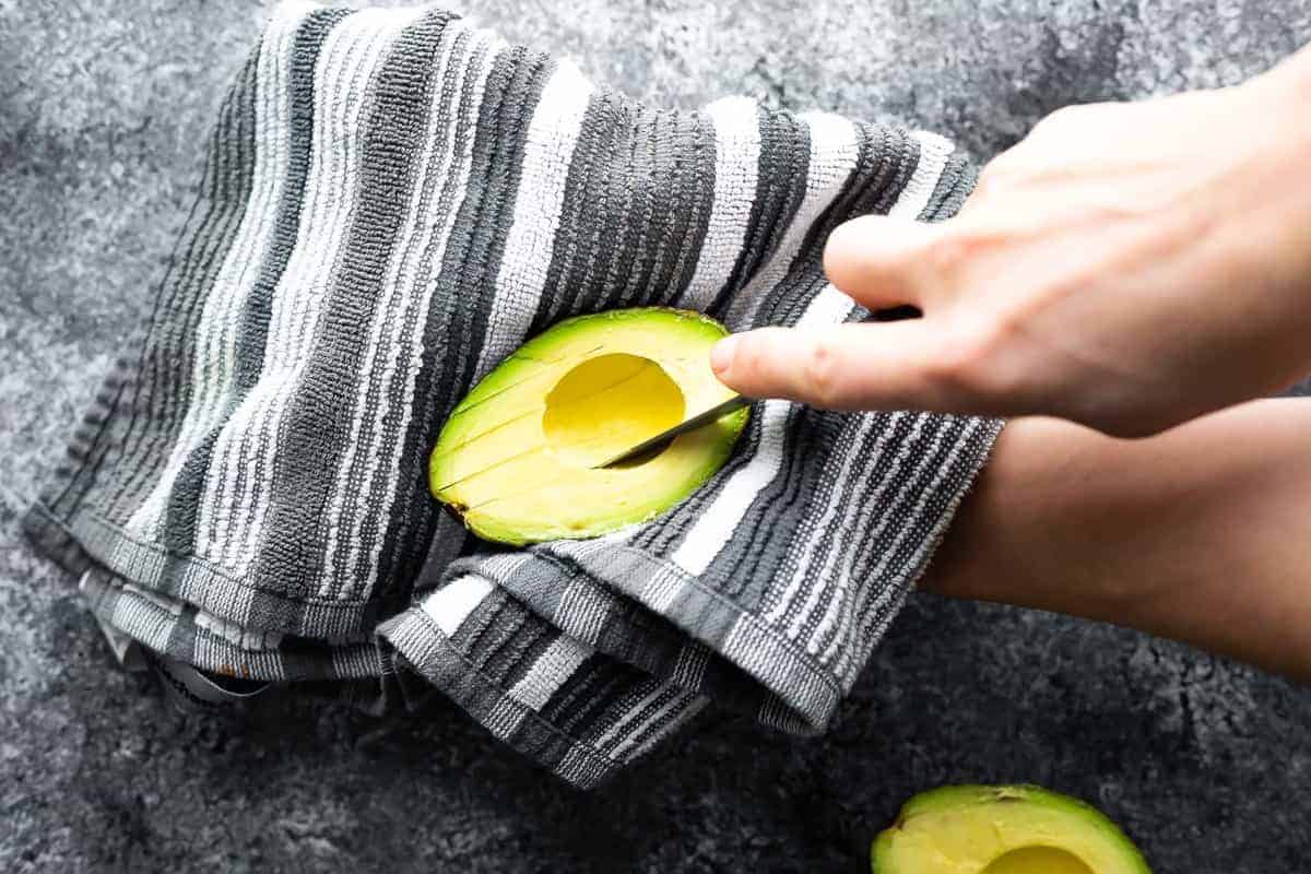 slicing into an avocado resting on a towel