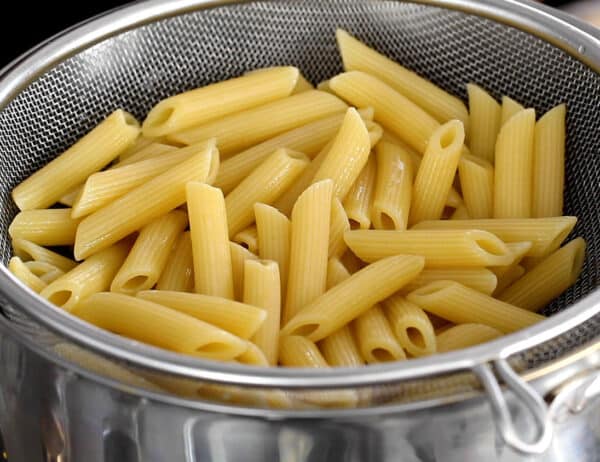 cooked penne pasta in colander sitting in a pot