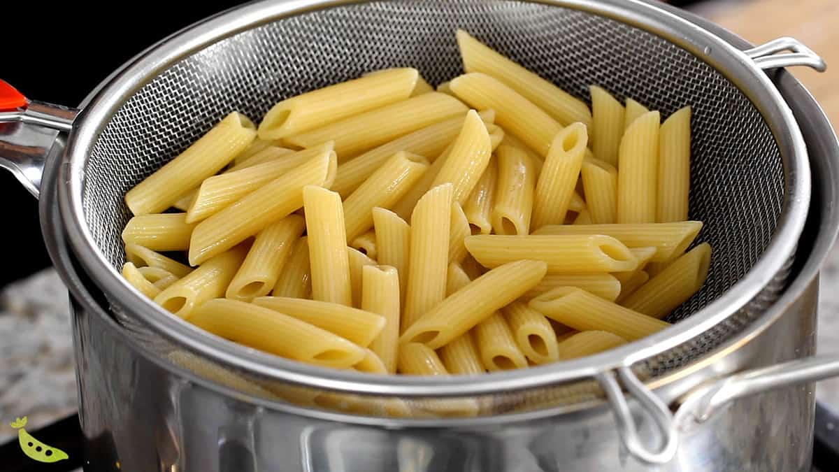 cooked penne pasta sitting in colander inside a pot