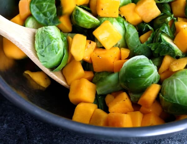 tossing brussels sprouts and butternut squash in oil