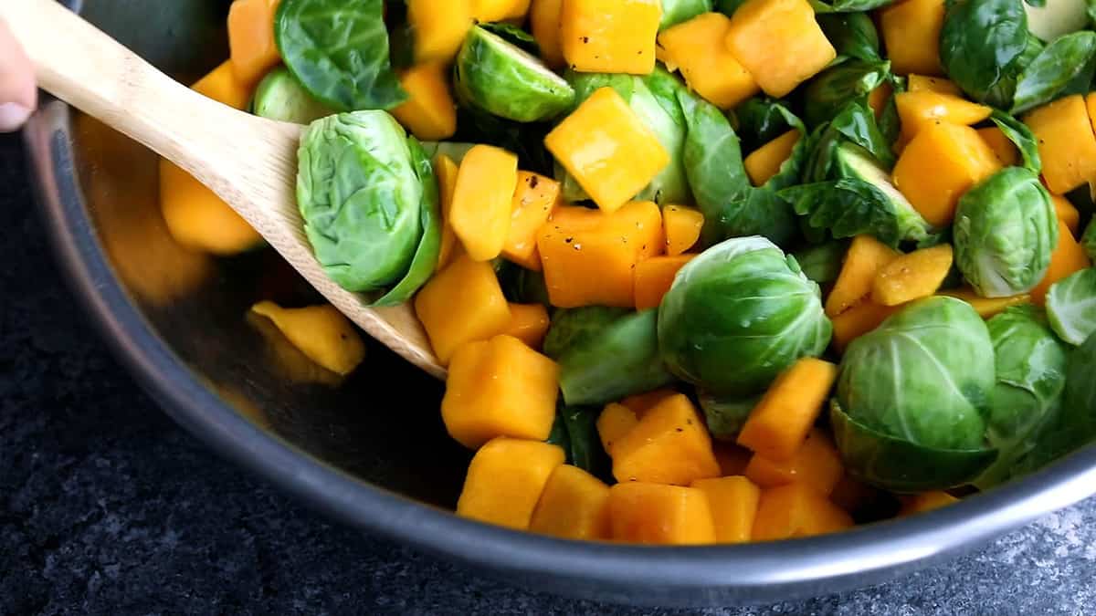 tossing brussels sprouts and butternut squash in oil