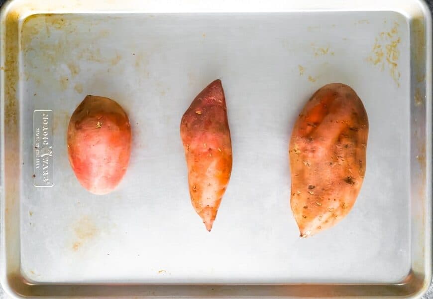 baked sweet potato recipe- different sized sweet potatoes on baking sheet before baking