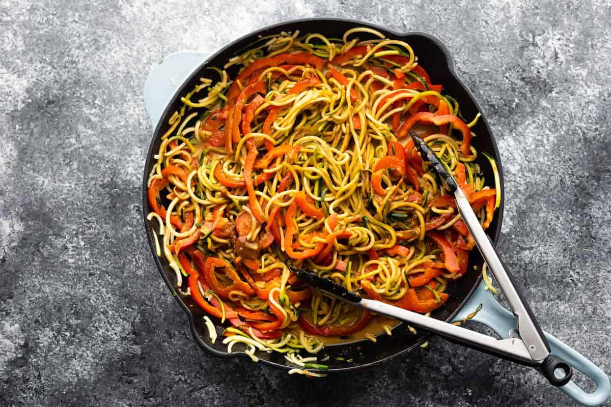 zucchini noodles and sliced red pepper tossed in peanut sauce