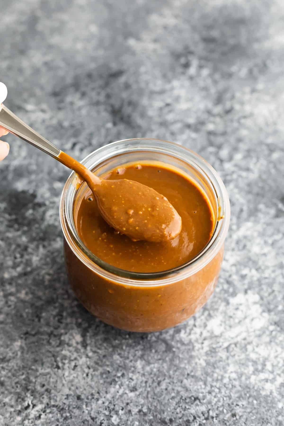 spoon showing texture of peanut sauce in jar