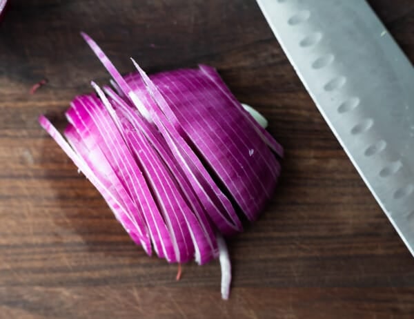 thinly sliced red onion on cutting board
