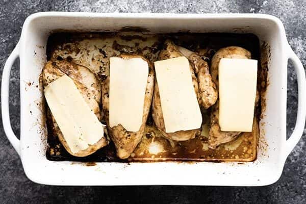 baked chicken in white casserole dish from overhead with cheese slices on top