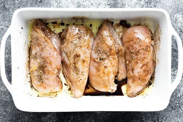 chicken breasts in white casserole dish with marinade from overhead