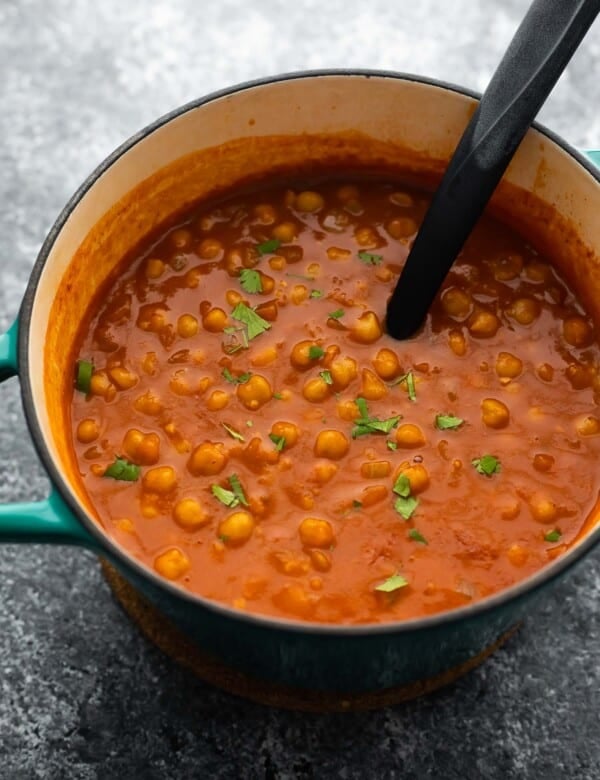 chickpea curry in blue pot with spoon