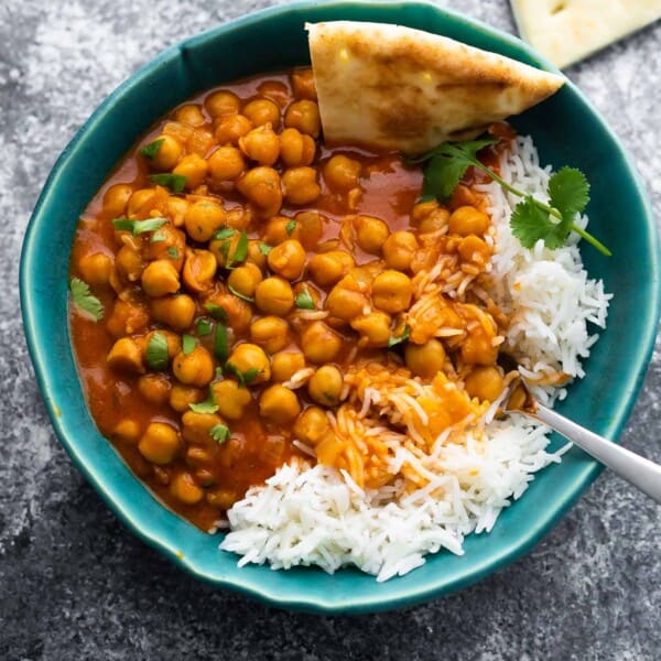 chickpea curry in bowl with rice and naan bread