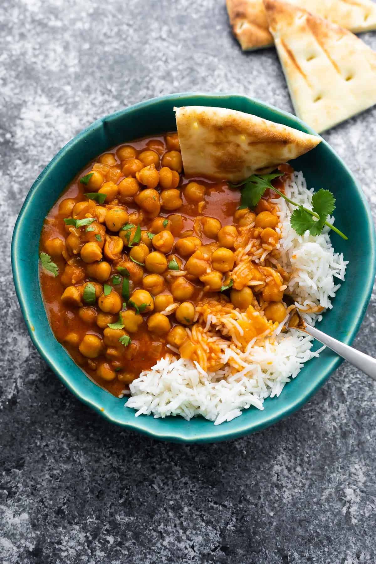chickpea curry in bowl with rice and naan bread