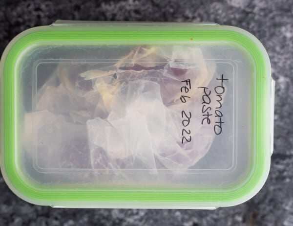 meal prep container labelled 'tomato paste feb 2022'