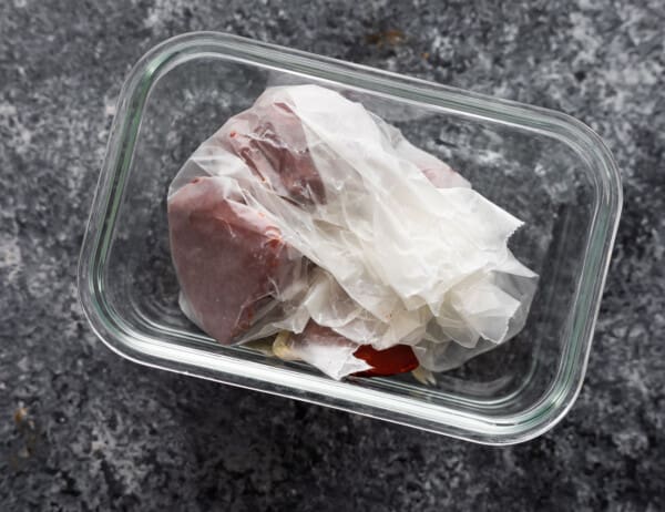 frozen tomato paste wrapped in wax paper inside a meal prep container
