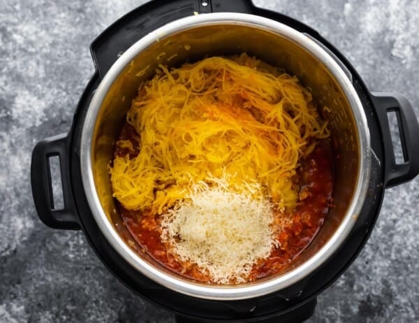 adding spaghetti squash noodles and parmesan cheese to meatsauce in instant pot
