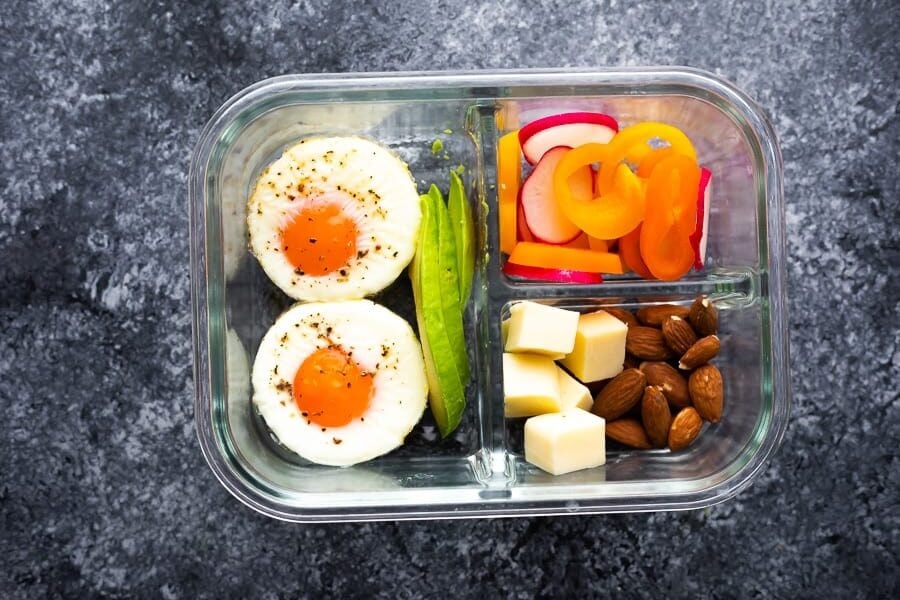 meal prep baked eggs in bento box with low carb sides including bell peppers, cheese, almonds, and avocado