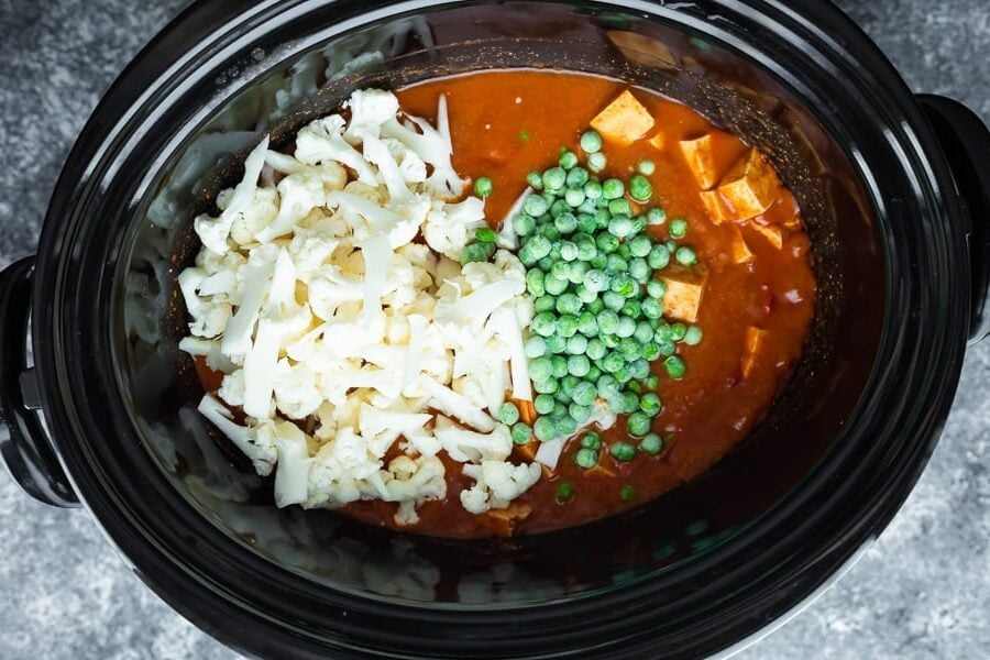 overhead view of slow cooker tikka masala in slow cooker with veggies added