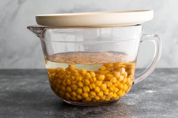 dried chickpeas soaking in large measuring cup, covered with a plate