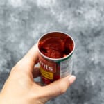 holding a nearly full can of tomato paste
