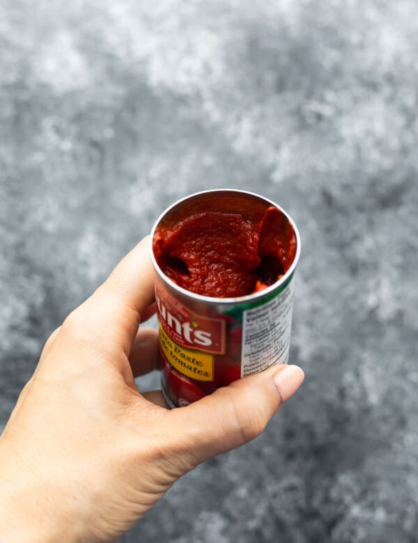 holding a nearly full can of tomato paste