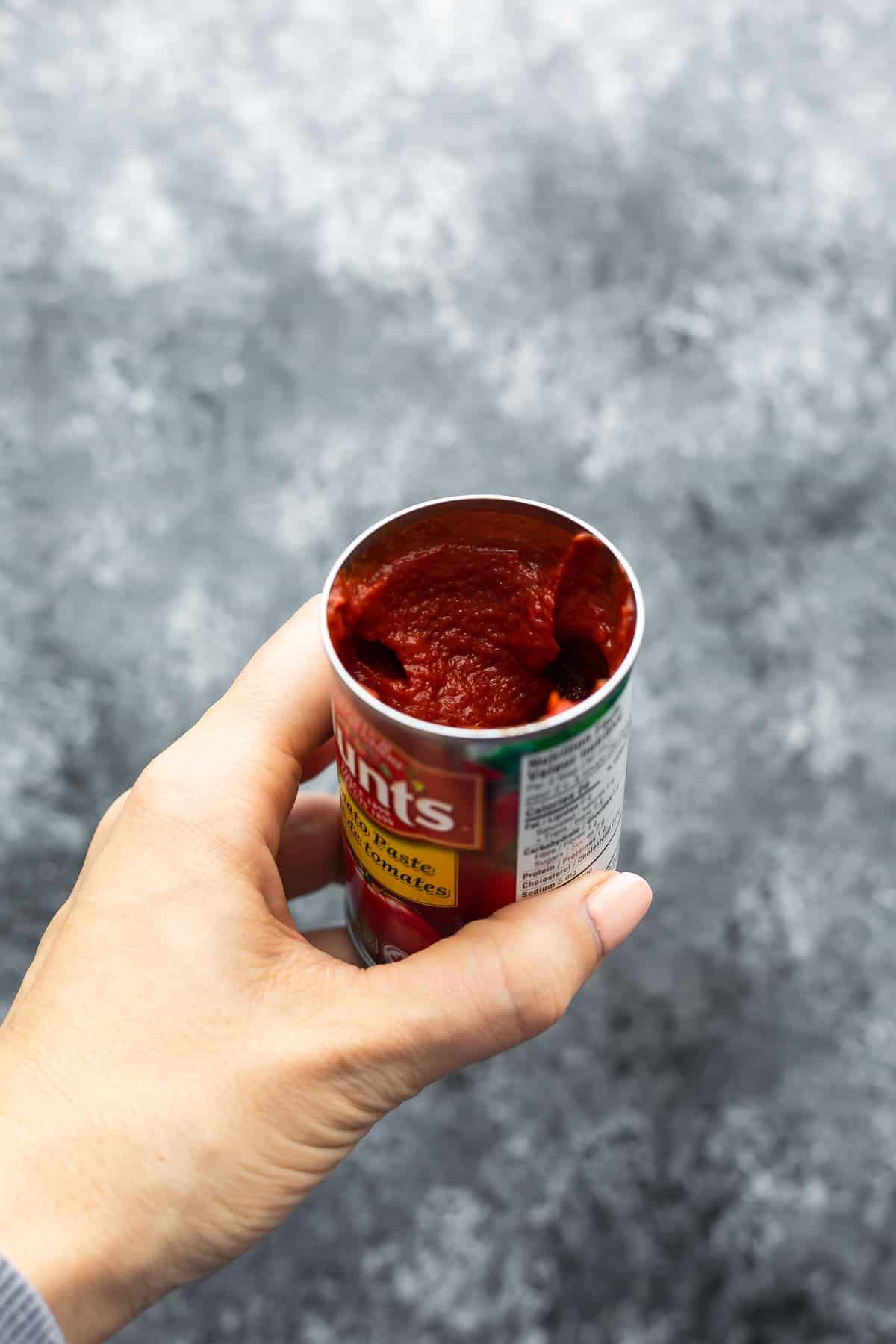 holding a nearly full can of tomato paste