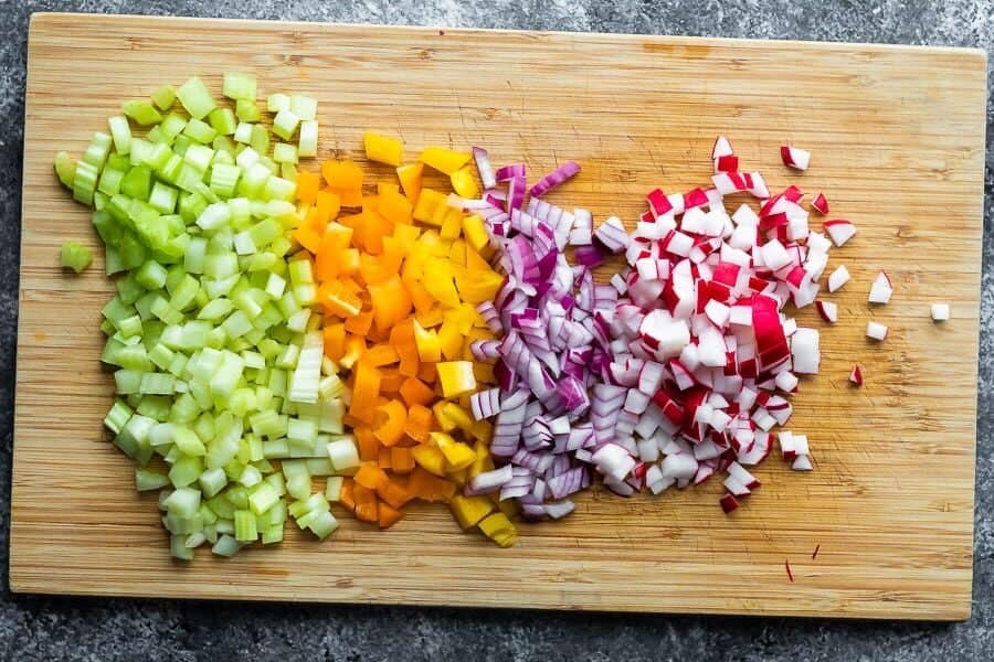 chopped celery, peppers, red onion, and radishes on cutting board from overhead