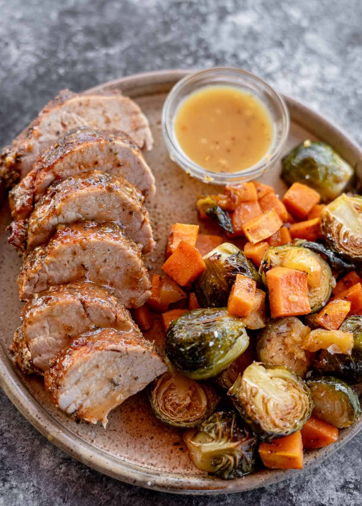 a plateful of roasted pork tenderloin with brussels sprouts and sweet potatoes