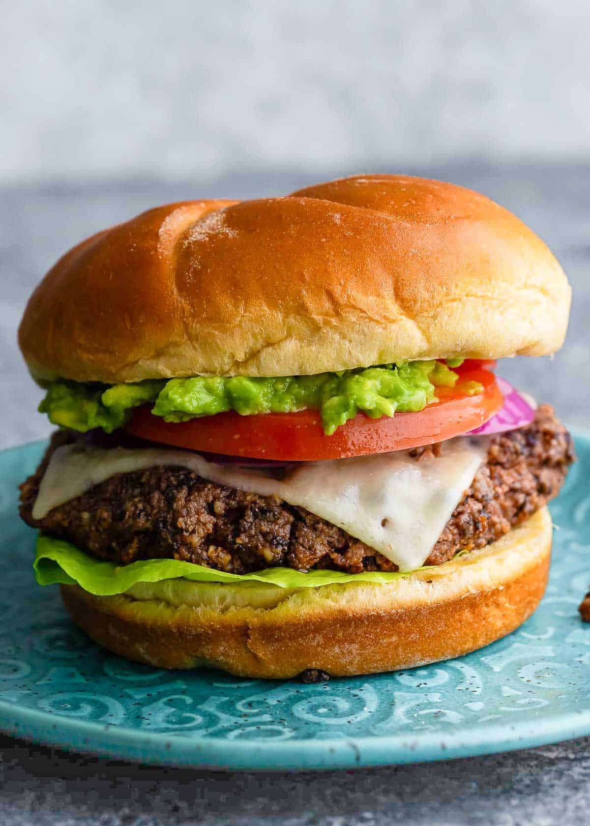 a black bean burger on a bun with tomato, avocado and lettuce