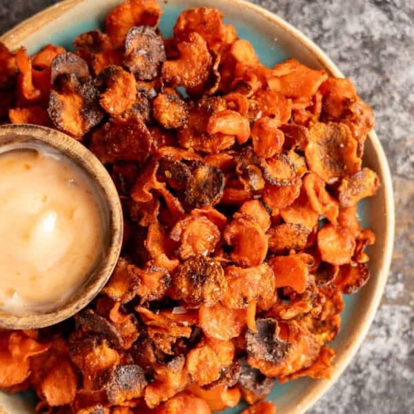 an overhead shot of crispy carrot chips with a dipping sauce