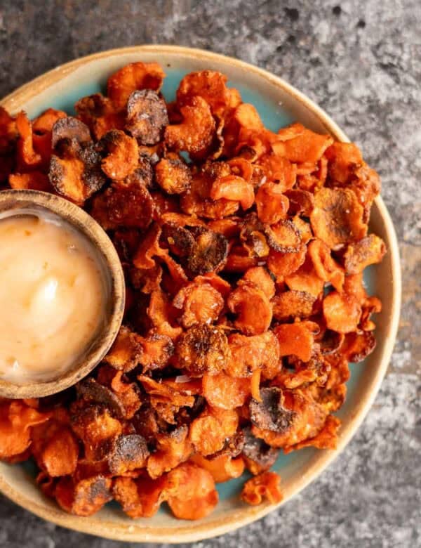 an overhead shot of crispy carrot chips with a dipping sauce