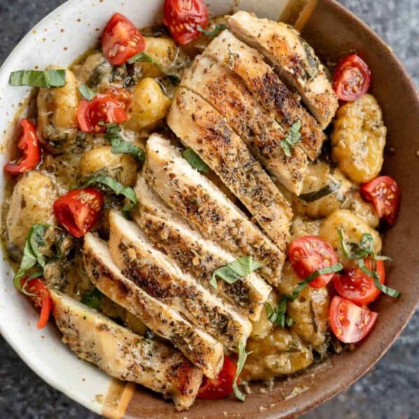 An overhead shot of pesto gnocchi in a bowl with sliced chicken
