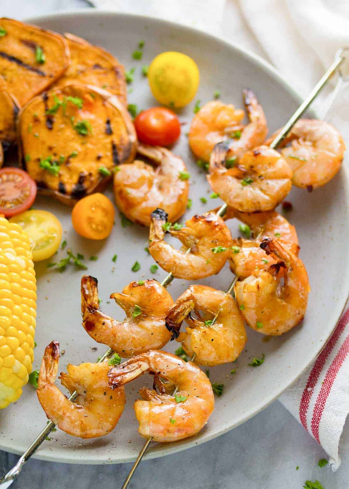 chipotle shrimp skewers on a plate with summer veggies