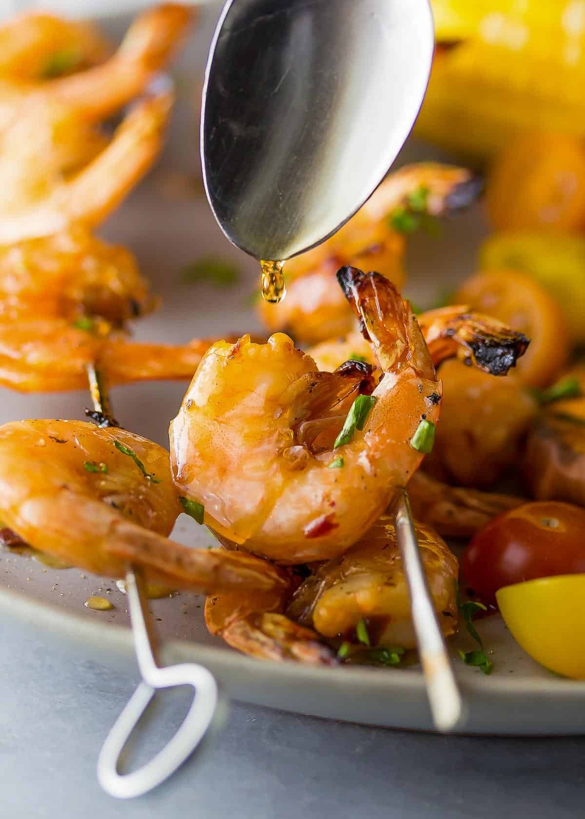 a spoon dripping maple syrup on grilled chipotle shrimp