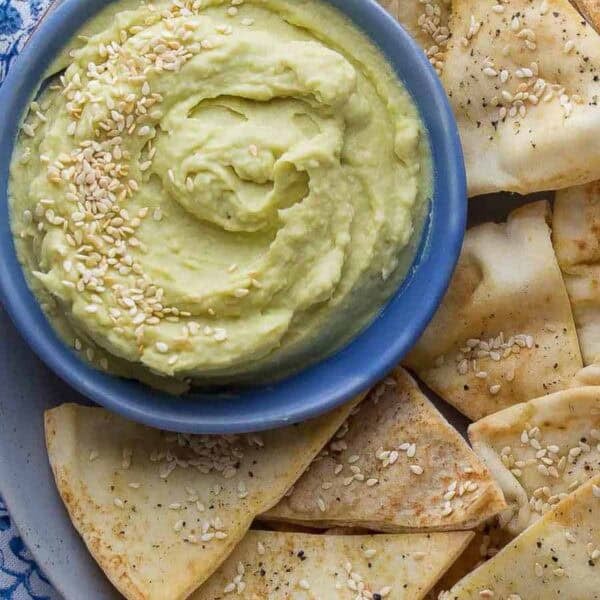 ultra creamy spicy white bean dip in a bowl with a side of freshly baked pita chips