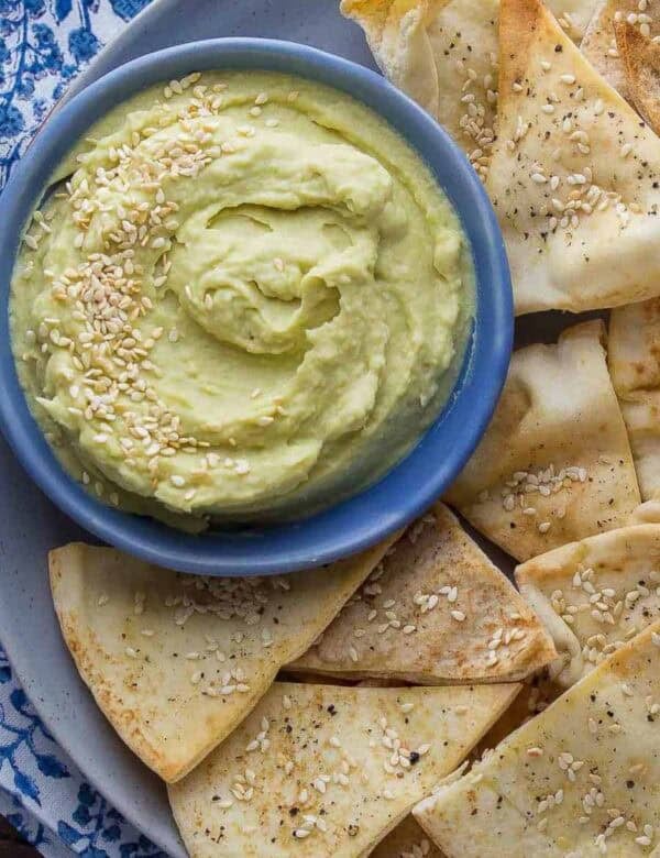 ultra creamy spicy white bean dip in a bowl with a side of freshly baked pita chips