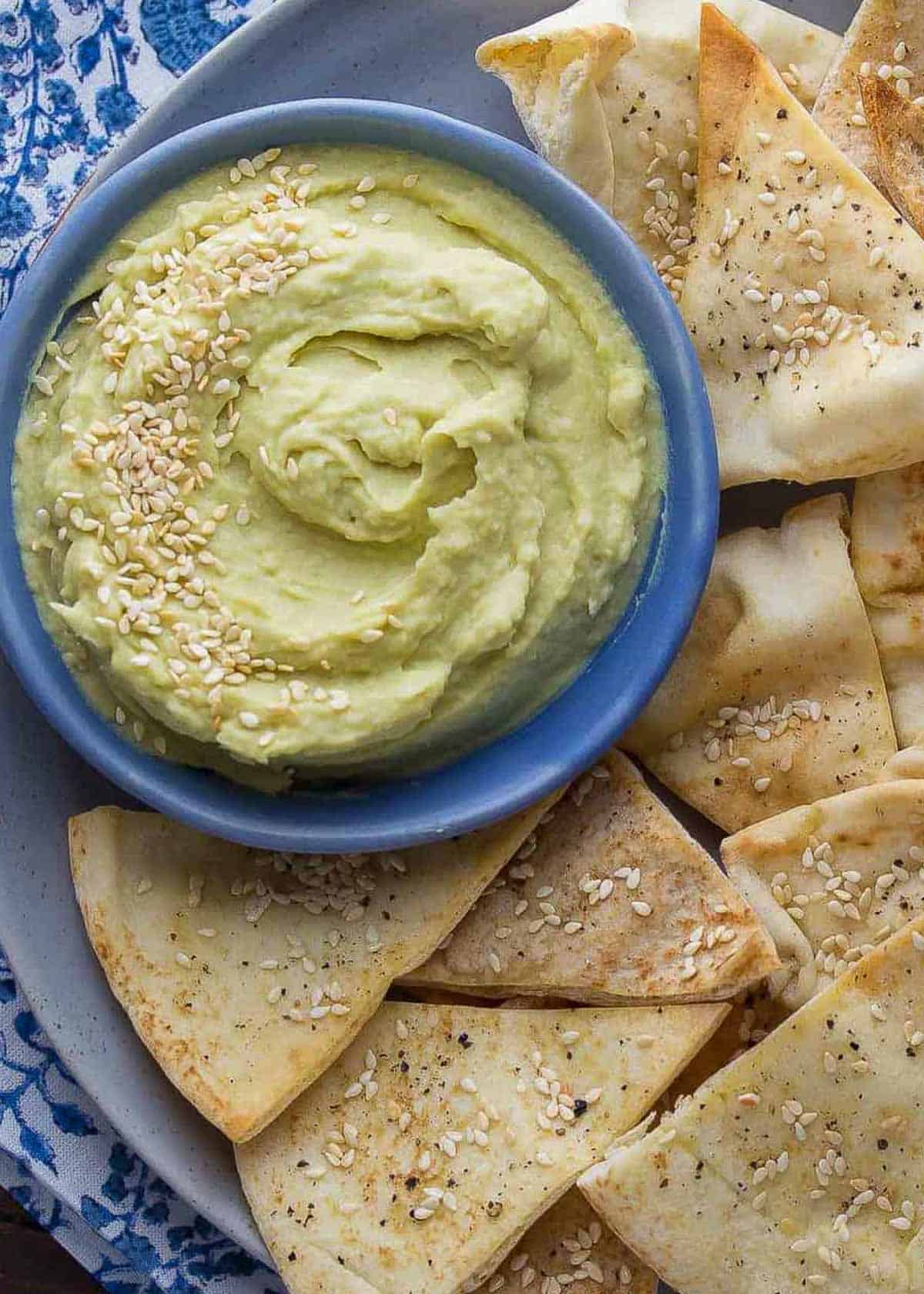 ultra creamy spicy white bean dip in a bowl with a side of freshly baked pita chips
